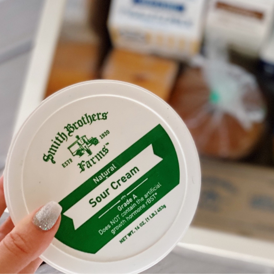 A hand holding Smith Brothers Farms Sour Cream